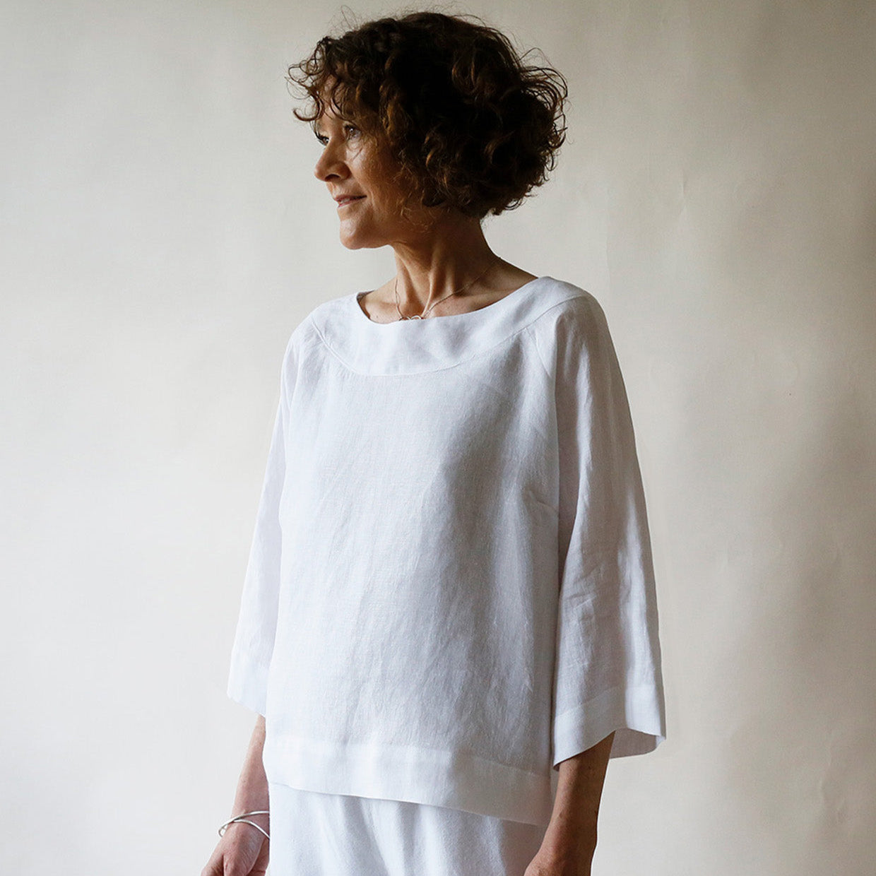 Woman wearing a white outfit against a plain background