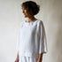 Woman wearing a white outfit against a plain background
