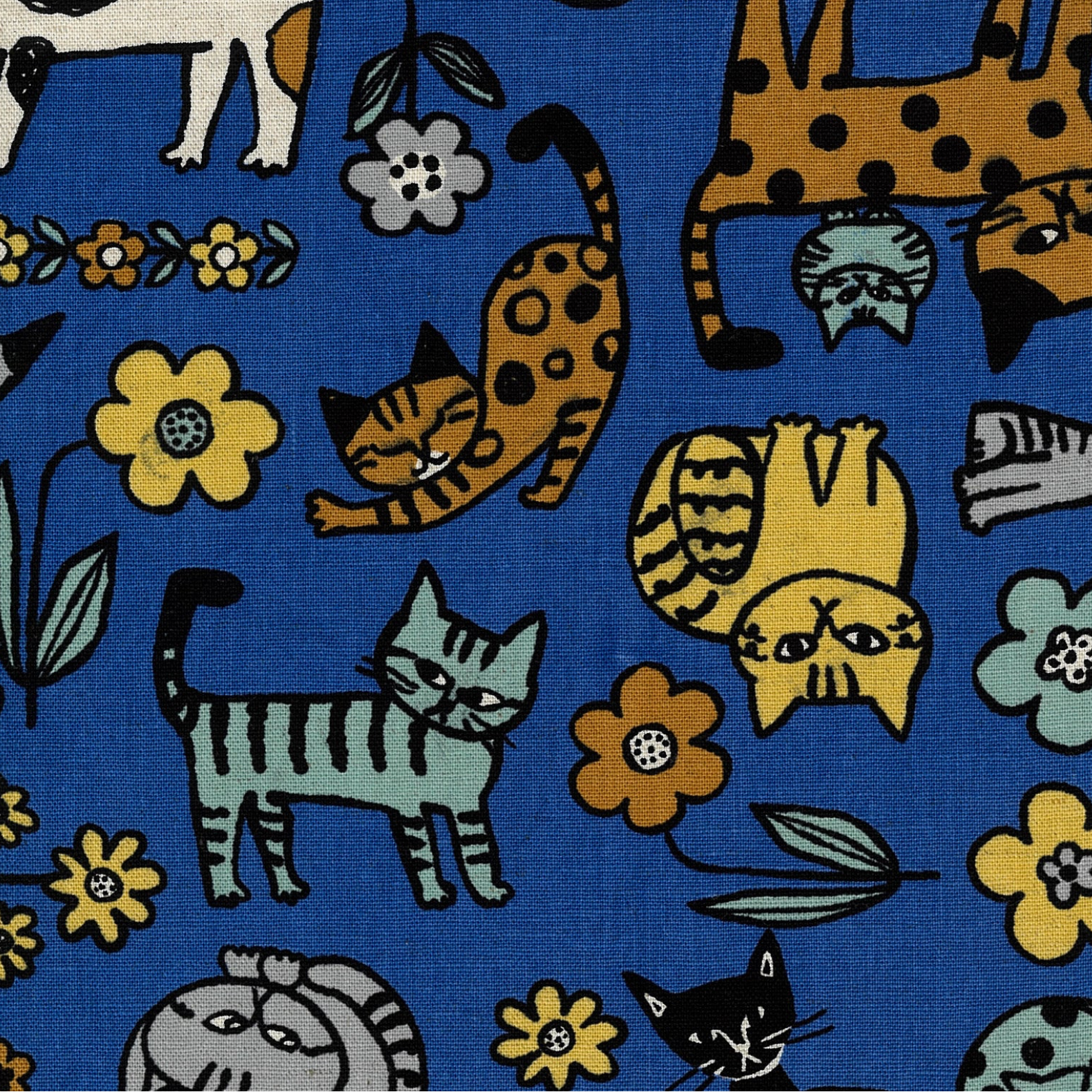 A close-up of a blue fabric with a playful, retro-style pattern of cartoon cats in orange, yellow, green, and black, interspersed with yellow and light blue flowers.
