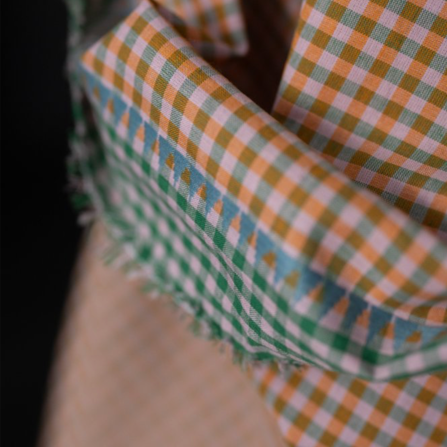 Folded orange and ecru gingham fabric with a light blue and green border.