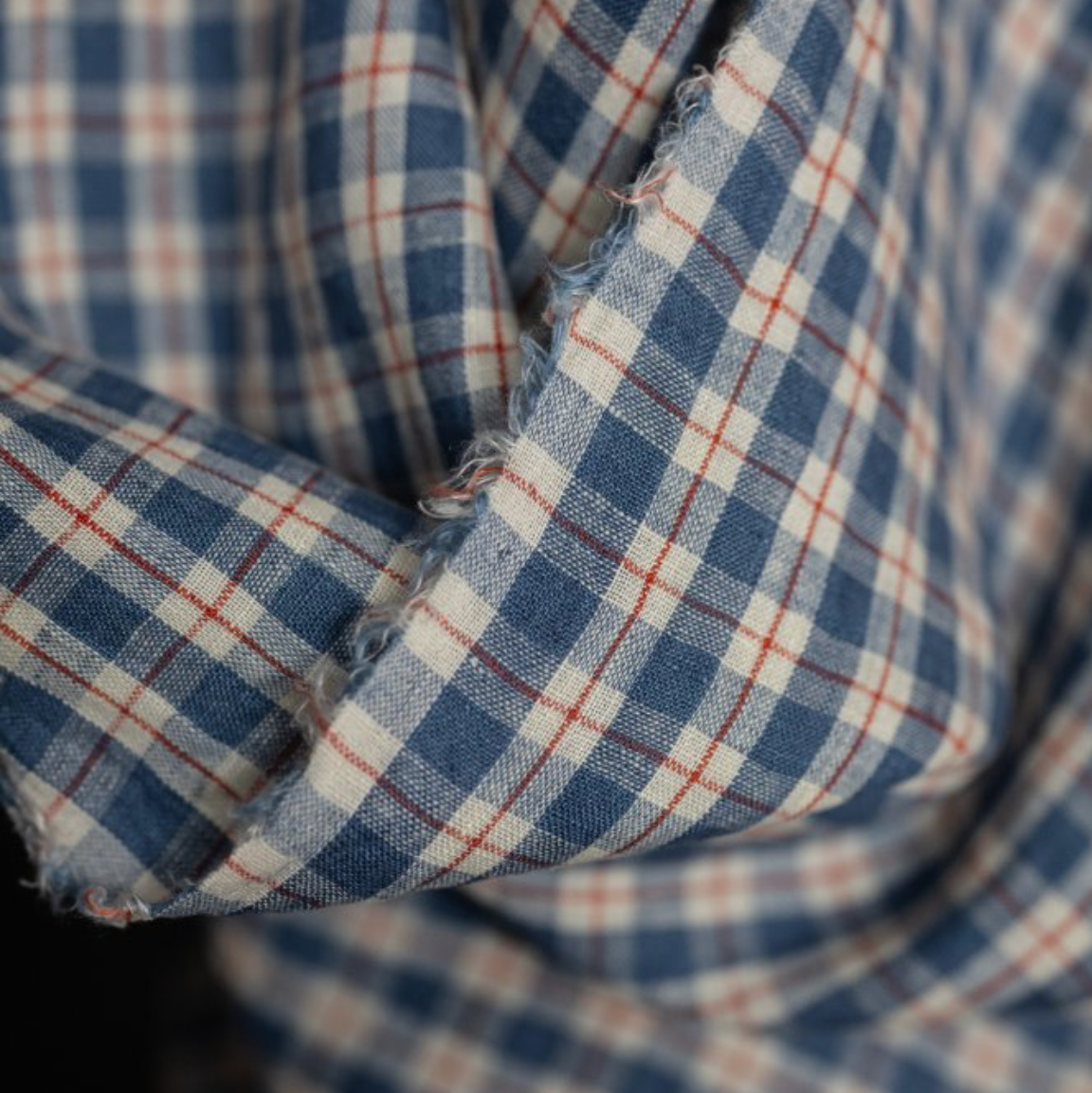 Close-up of a plaid fabric with a blue, white, and red checkered pattern.